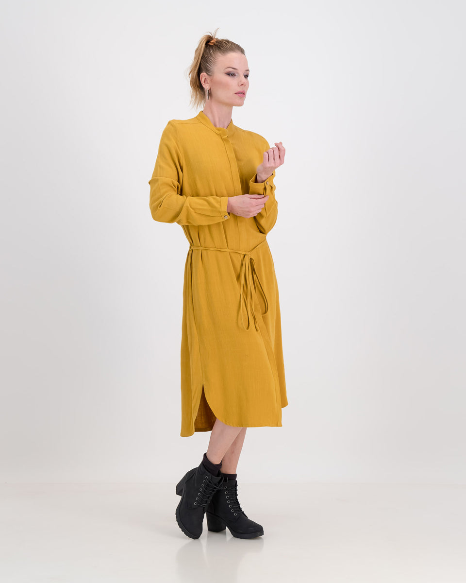 A lovely woman wears the imogen dress in mustard ochre, the autumnal tone is perfect for colder days. The dress has a concealed button stand and the rich linen/rayon blend fabric sits below the knee. The imogen also features long-sleeves that can be rolled up and ruched for a styling effect.