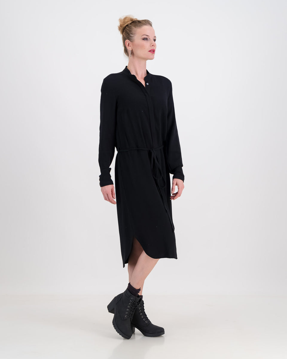 A vibrant woman wearing a classic imogen dress by LUNAR. The dress is below-knee length with a hidden button stand and long sleeves.