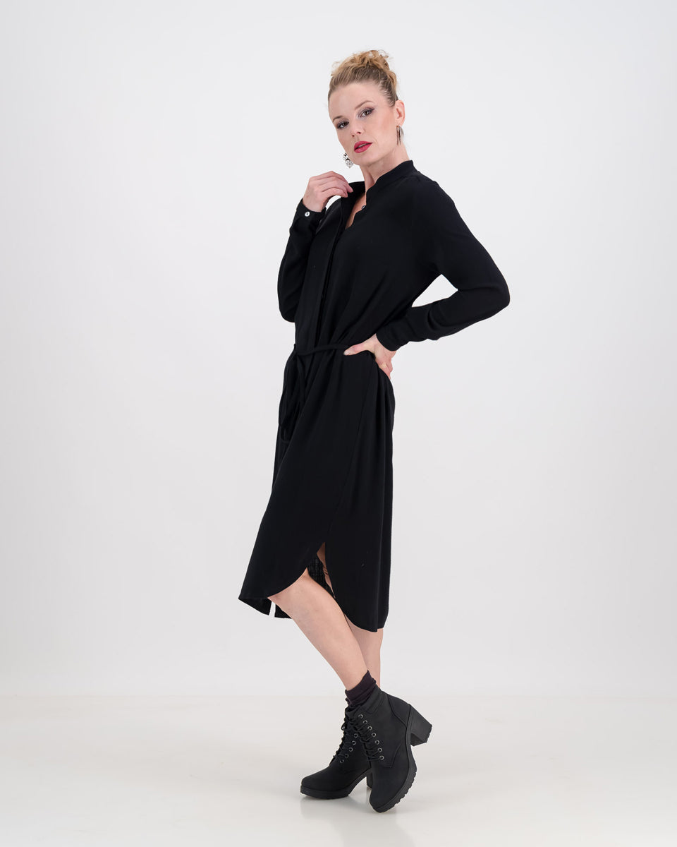 A vibrant woman wearing a classic imogen dress by LUNAR. The dress is below-knee length with a hidden button stand and long sleeves.