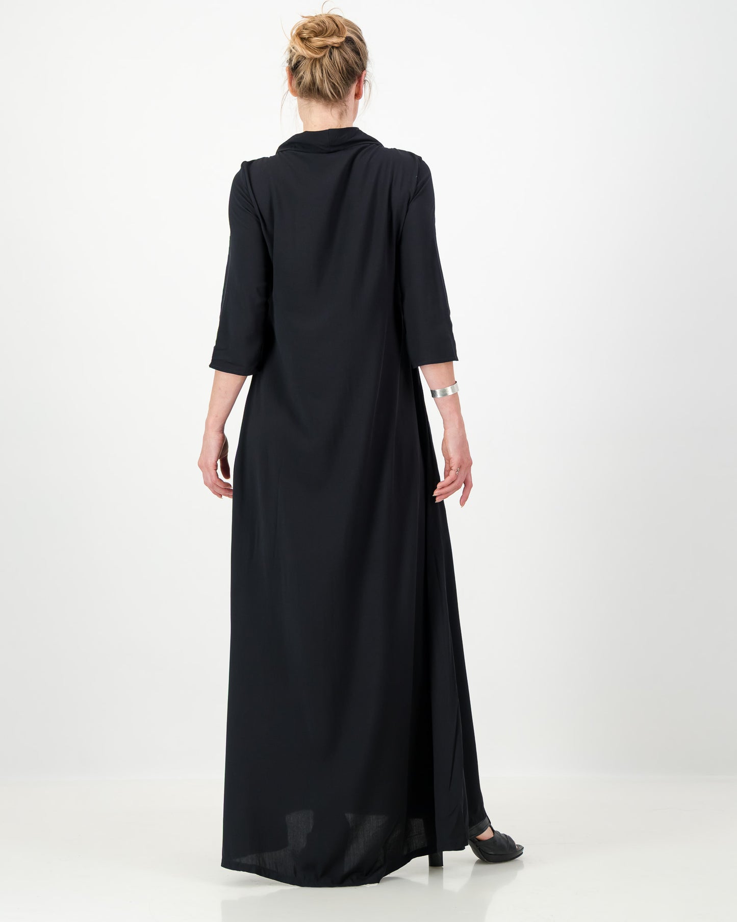 Model wearing a black dress from the back on a white background.