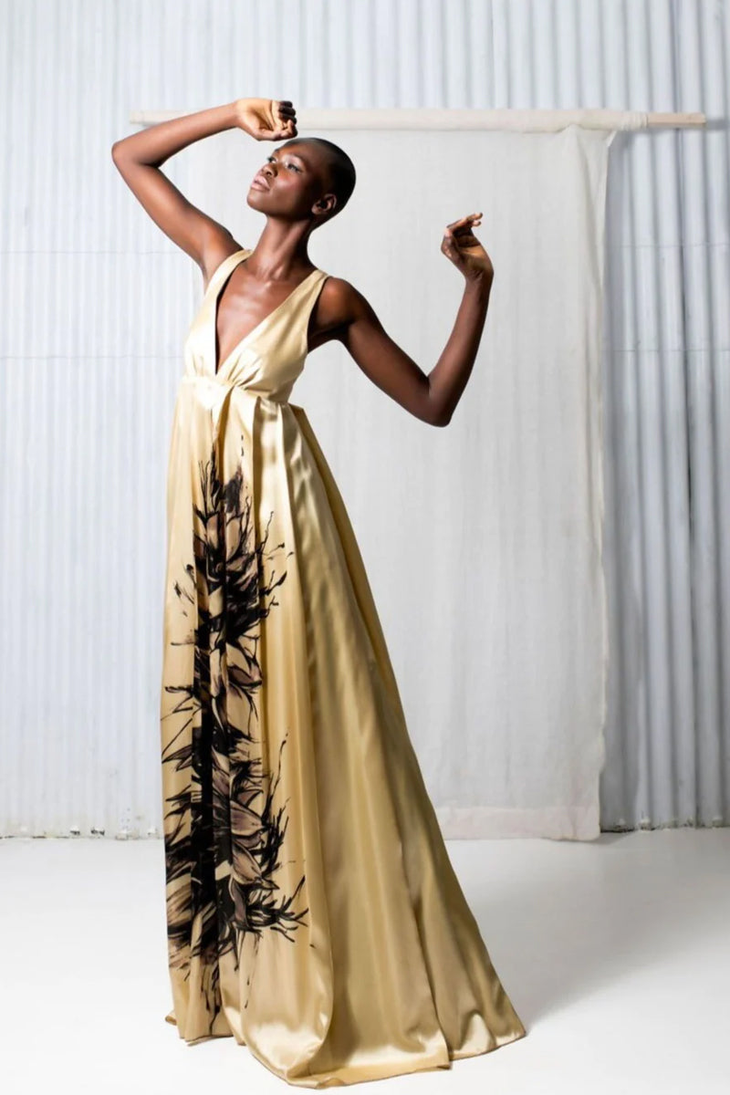 Elegant woman in gold silk wedding dress with black and white floral art, empire waist, and v neckline.