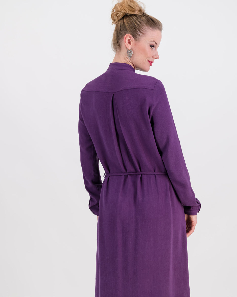 The deep purple imogen dress is shown here on a younger woman. She wears it effortlessly as the waist is cinched in with the built-in belt. The heavier linen/rayon blend fabric lets the dress fall beautifully and sits below the knee. The long sleeves of the dress can be worn ruched up or down depending on the weather.