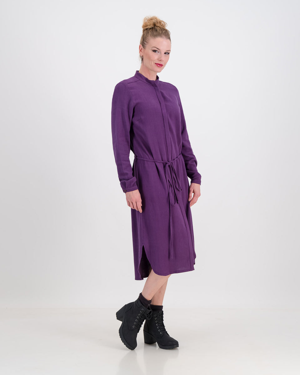 The deep purple imogen dress is shown here on a younger woman. She wears it effortlessly as the waist is cinched in with the built-in belt. The heavier linen/rayon blend fabric lets the dress fall beautifully and sits below the knee. The long sleeves of the dress can be worn ruched up or down depending on the weather.