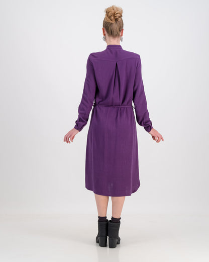 The deep purple imogen dress is shown here on a younger woman. She wears it effortlessly as the waist is cinched in with the built-in belt. The heavier linen/rayon blend fabric lets the dress fall beautifully and sits below the knee. The long sleeves of the dress can be worn ruched up or down depending on the weather.