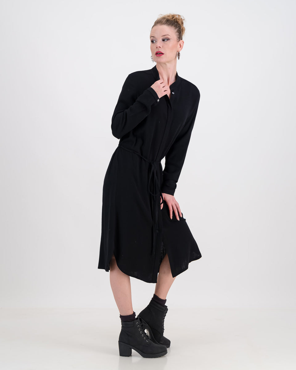 A vibrant woman wearing a classic imogen dress by LUNAR. The dress is below-knee length with a hidden button stand and long sleeves.