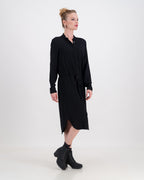 A vibrant woman wearing a classic imogen dress by LUNAR. The dress is below-knee length with a hidden button stand and long sleeves.