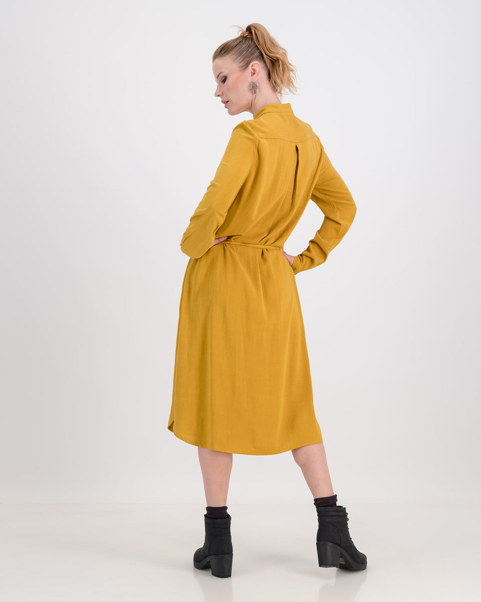 A lovely woman wears the imogen dress in mustard ochre, the autumnal tone is perfect for colder days. The dress has a concealed button stand and the rich linen/rayon blend fabric sits below the knee. The imogen also features long-sleeves that can be rolled up and ruched for a styling effect.