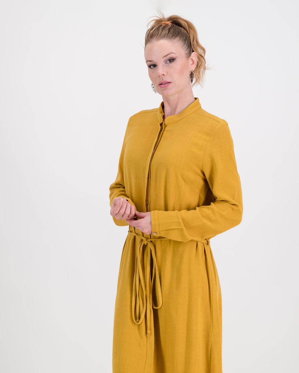 A lovely woman wears the imogen dress in mustard ochre, the autumnal tone is perfect for colder days. The dress has a concealed button stand and the rich linen/rayon blend fabric sits below the knee. The imogen also features long-sleeves that can be rolled up and ruched for a styling effect.
