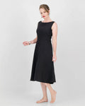 A model wearing a black sleeveless, boat neckline, fit and flare, knee-length dress with a center back zip.