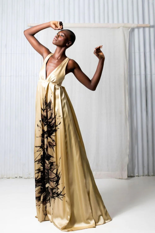  Elegant woman in gold silk wedding dress with black and white floral art, empire waist, and v neckline.