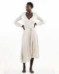 A model wearing a stone-colored eva wrap dress with a v-neckline, long sleeves, covered buttons, and an asymmetrical hem.