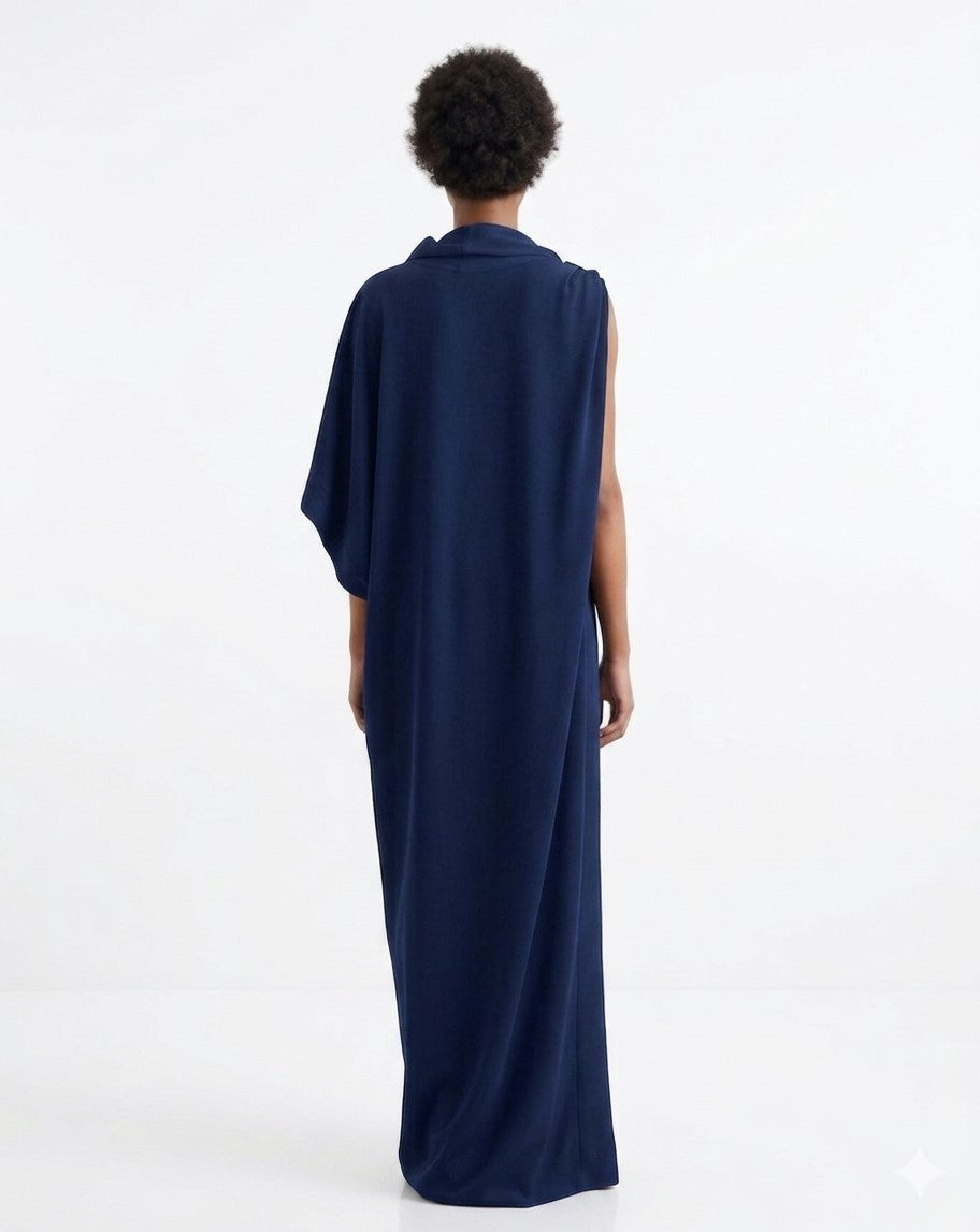 Back view of a woman wearing a navy blue loose fitting full-length dress with a white background. 