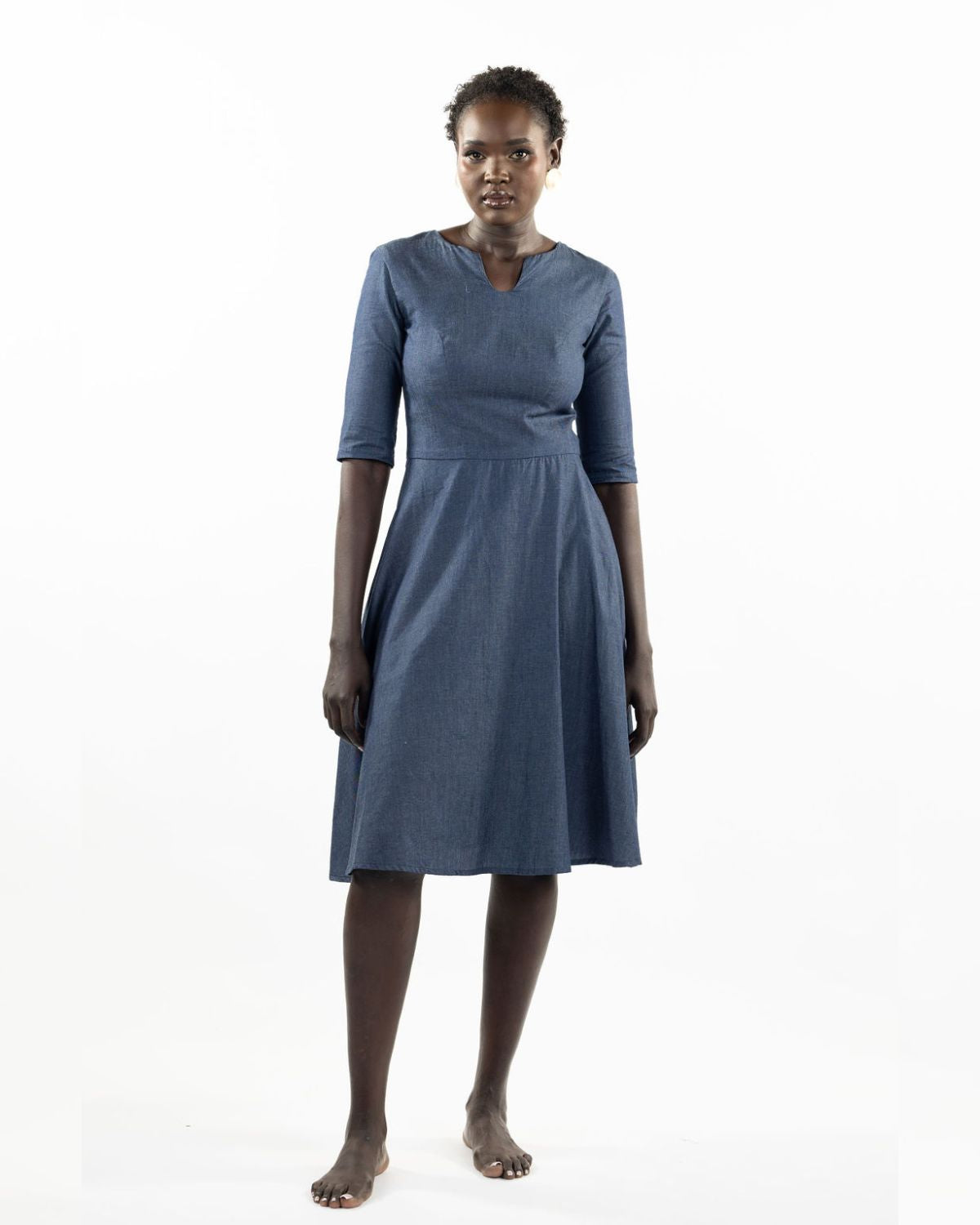This image features a model wearing the "Khloe Dress" in a denim design. The dress, tailored with a flattering A-line silhouette, reaches below the knees, making it a versatile piece for both casual and semi-formal wear.