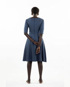 This image features a model wearing the "Khloe Dress" in a denim design. The dress, tailored with a flattering A-line silhouette, reaches below the knees, making it a versatile piece for both casual and semi-formal wear.