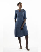 This image features a model wearing the "Khloe Dress" in a denim design. The dress, tailored with a flattering A-line silhouette, reaches below the knees, making it a versatile piece for both casual and semi-formal wear.