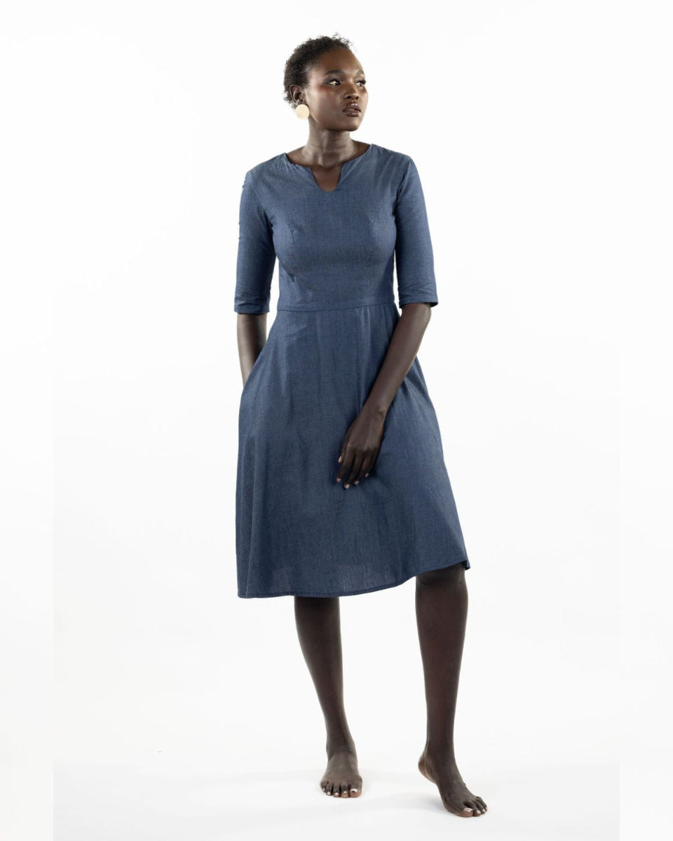 This image features a model wearing the "Khloe Dress" in a denim design. The dress, tailored with a flattering A-line silhouette, reaches below the knees, making it a versatile piece for both casual and semi-formal wear.