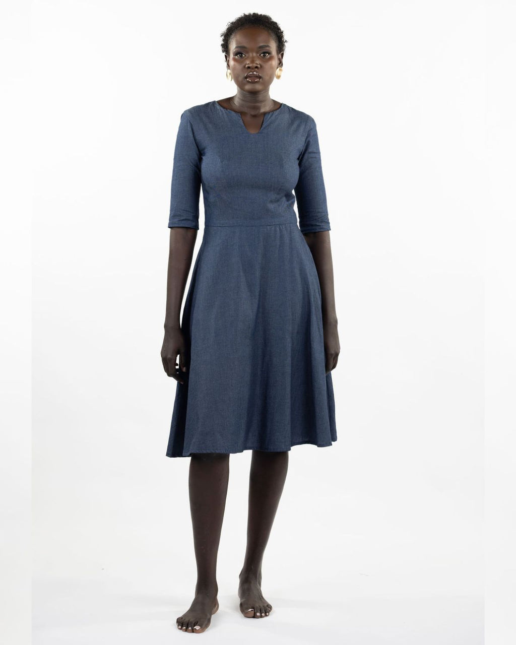 This image features a model wearing the "Khloe Dress" in a denim design. The dress, tailored with a flattering A-line silhouette, reaches below the knees, making it a versatile piece for both casual and semi-formal wear.