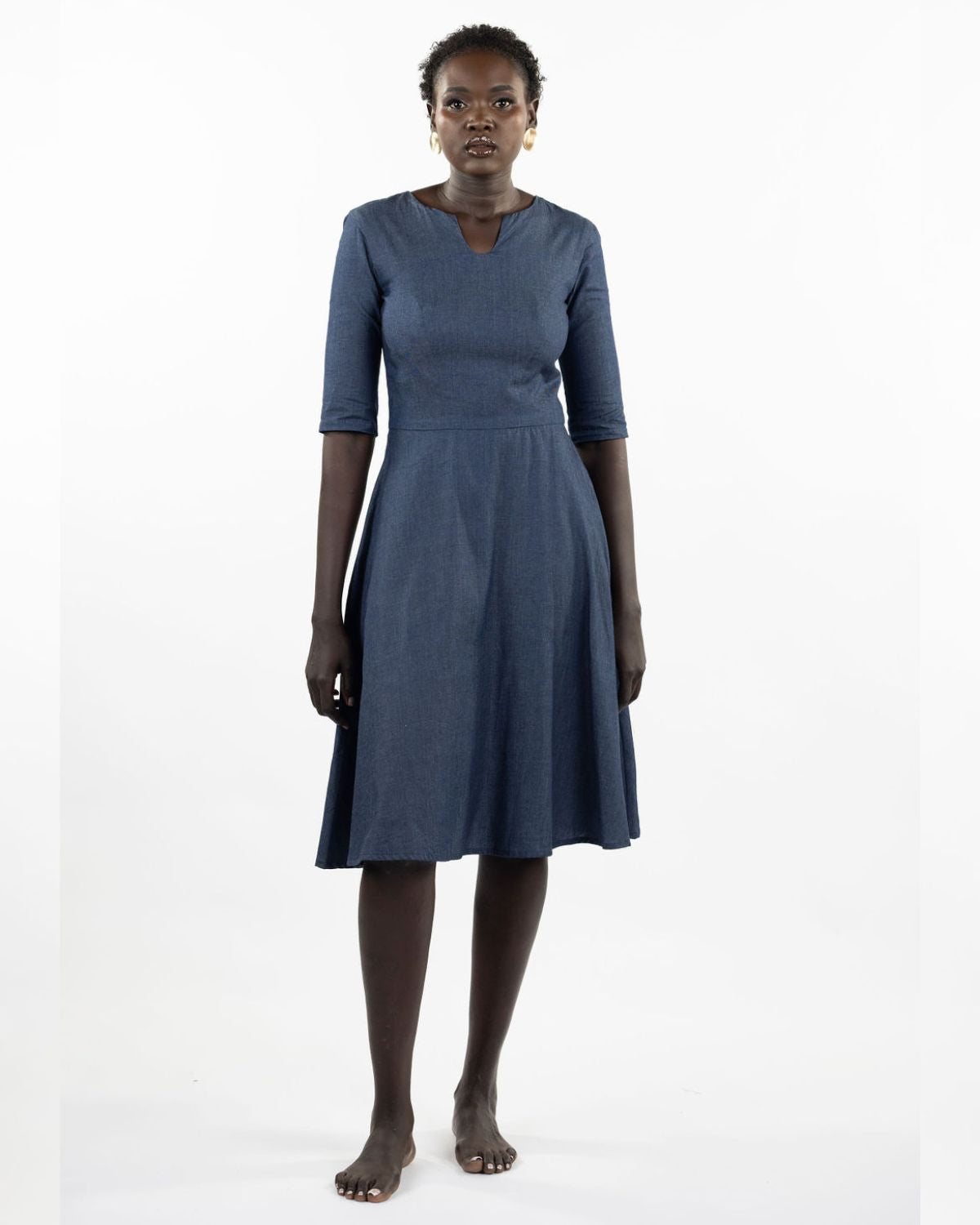 This image features a model wearing the "Khloe Dress" in a denim design. The dress, tailored with a flattering A-line silhouette, reaches below the knees, making it a versatile piece for both casual and semi-formal wear.