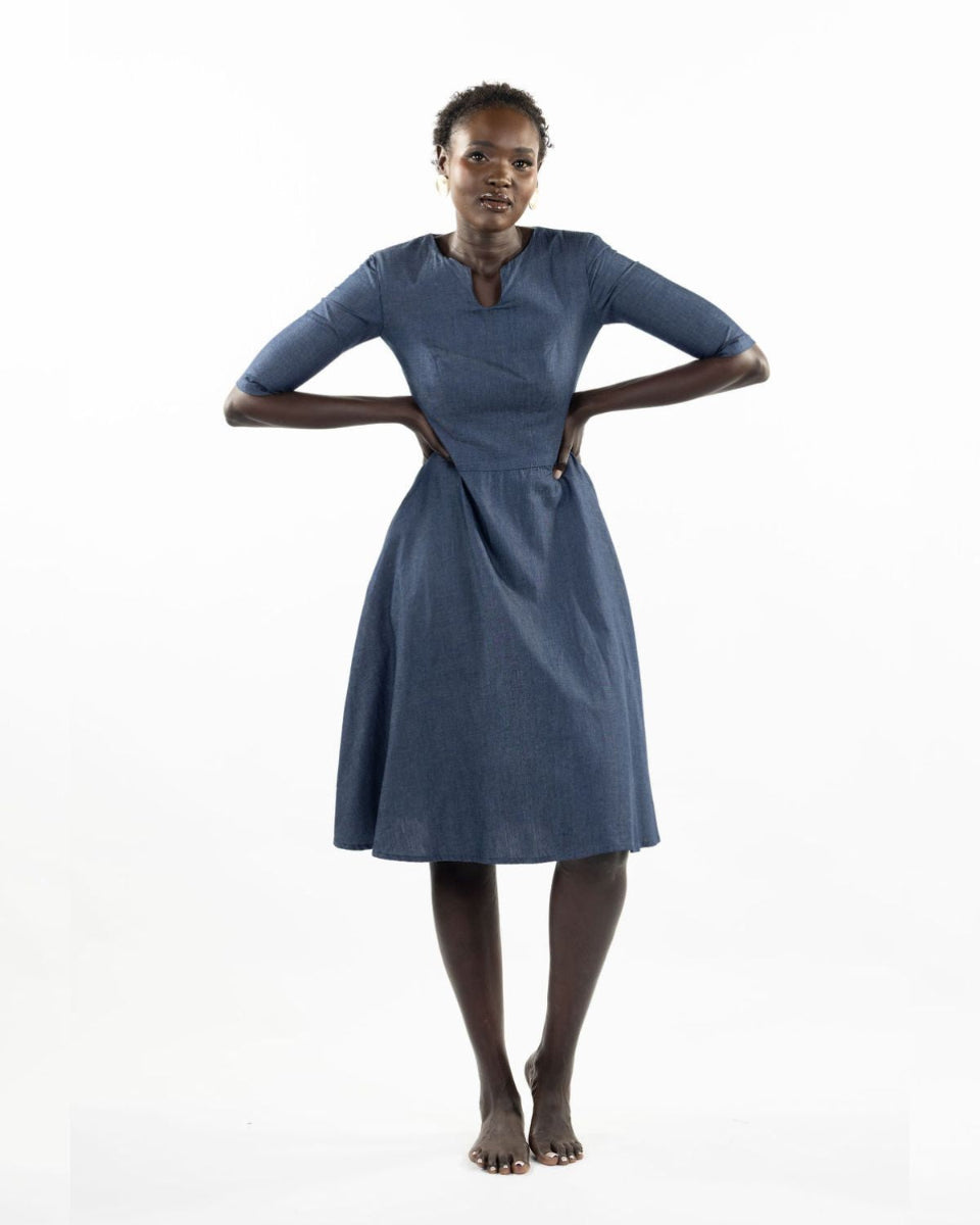 This image features a model wearing the "Khloe Dress" in a denim design. The dress, tailored with a flattering A-line silhouette, reaches below the knees, making it a versatile piece for both casual and semi-formal wear.