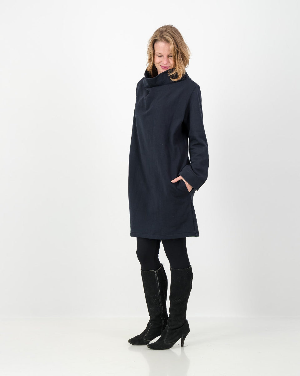 A black-colored winter dress with a cowl neckline, full-length sleeves, and a straight cut, worn by a lady with black boots and leggings.