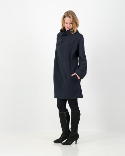 A black-colored winter dress with a cowl neckline, full-length sleeves, and a straight cut, worn by a lady with black boots and leggings.
