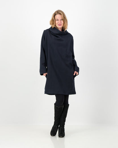 A black-colored winter dress with a cowl neckline, full-length sleeves, and a straight cut, worn by a lady with black boots and leggings.