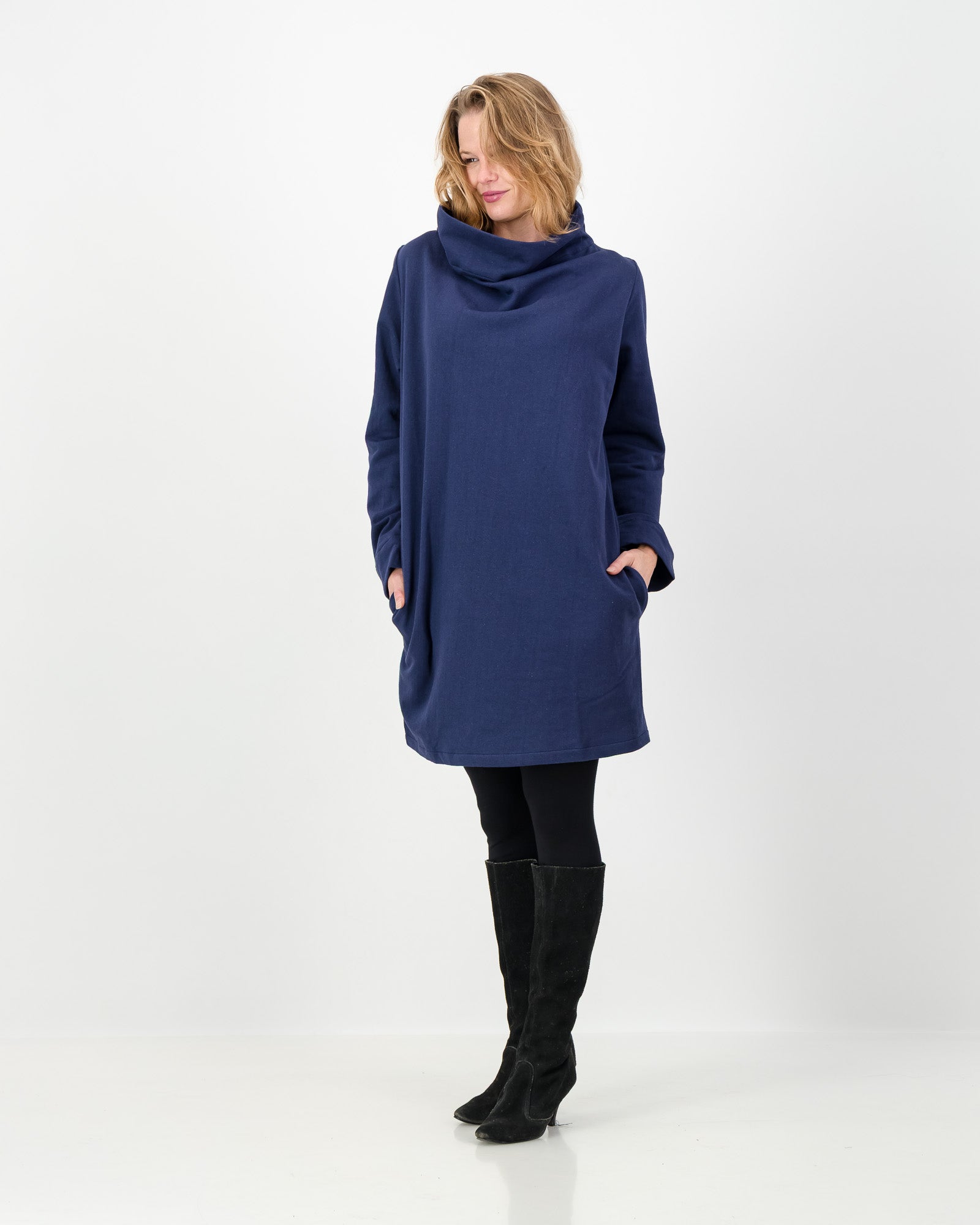 A navy-colored winter dress with a cowl neckline, full-length sleeves, and a straight cut, worn by a lady with black boots and leggings.