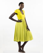 A woman models a chartreuse-colored knee-length dress with a gathered skirt and a V-neckline. The dress features cap sleeves and a flattering waist cinch.