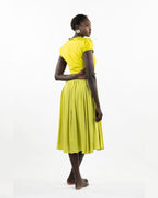 A woman models a chartreuse-colored knee-length dress with a gathered skirt and a V-neckline. The dress features cap sleeves and a flattering waist cinch.