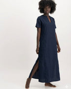 Woman wearing a long navy dress with a V-neck and side slits on a white background