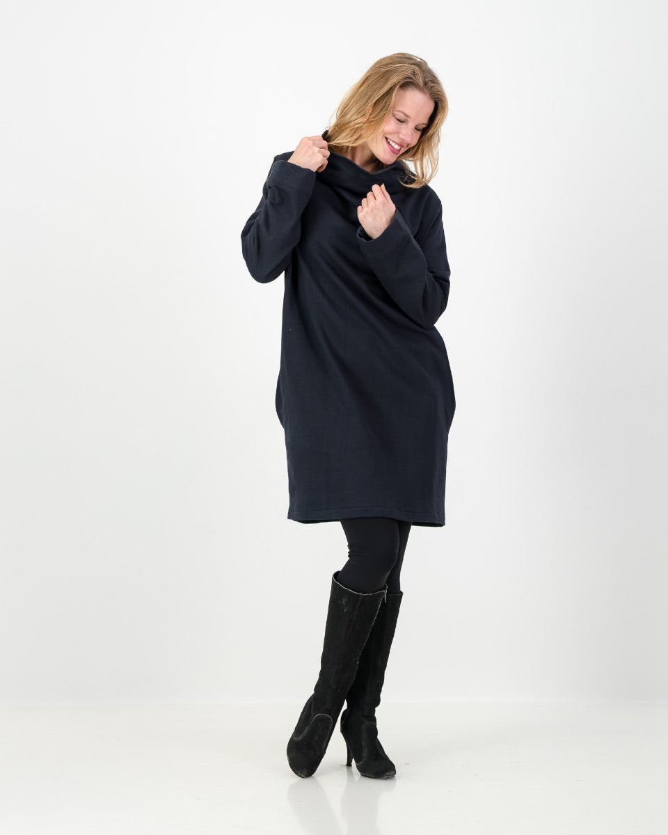 A black-colored winter dress with a cowl neckline, full-length sleeves, and a straight cut, worn by a lady with black boots and leggings.