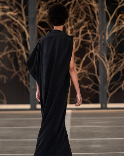 Model wearing a black LUNAR kari dress. Loose fitting dress on SA Fashion Week runway. Back view